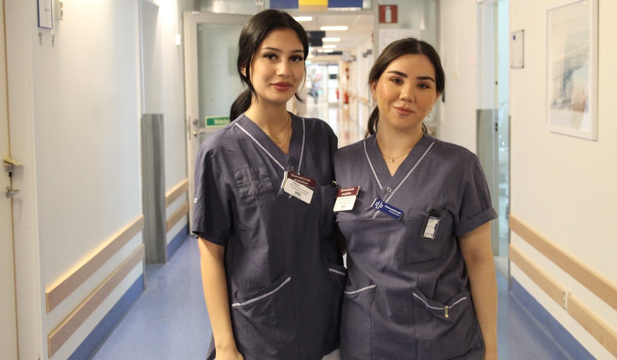 två kvinnor i vårdkläder tillsammans i sjukhuskorridor