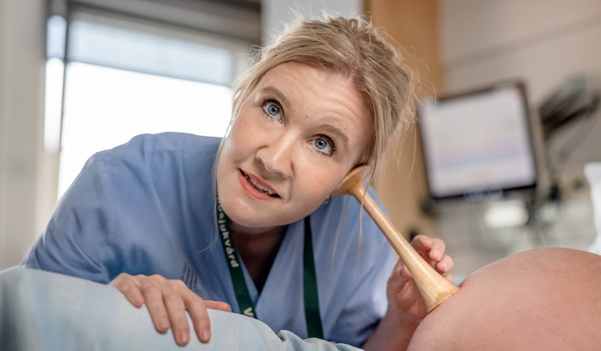 Barnmorska lyssnar med tratt på gravid mage.