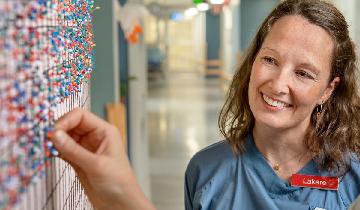 kvinna framför vägg med nålar