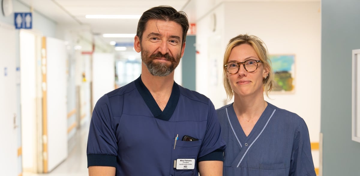 man och kvinna klädda i sjukhuskläder står i korridor