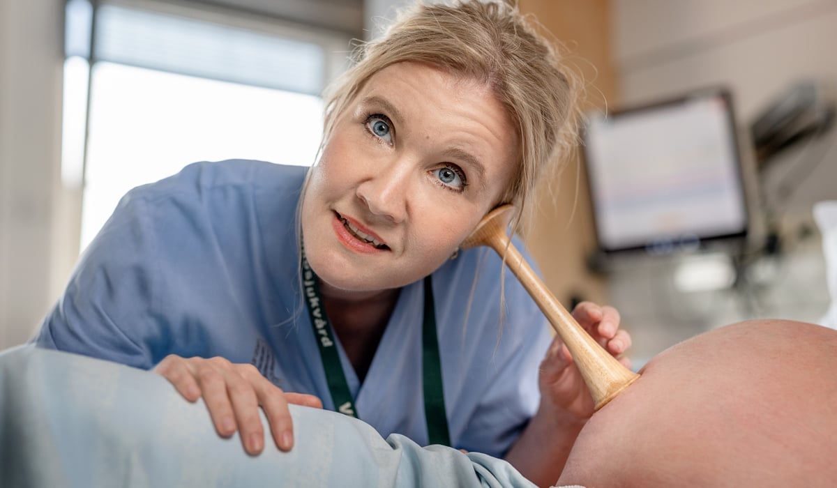 Barnmorska lyssnar med tratt på gravid mage.